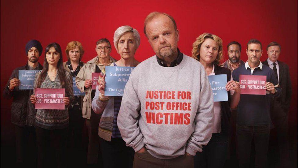 The cast in Mr Bates vs the Post Office looking directly into camera. Toby Jones, who played Alan Bates, is wearing a jumper saying Justice For Post Office Victims