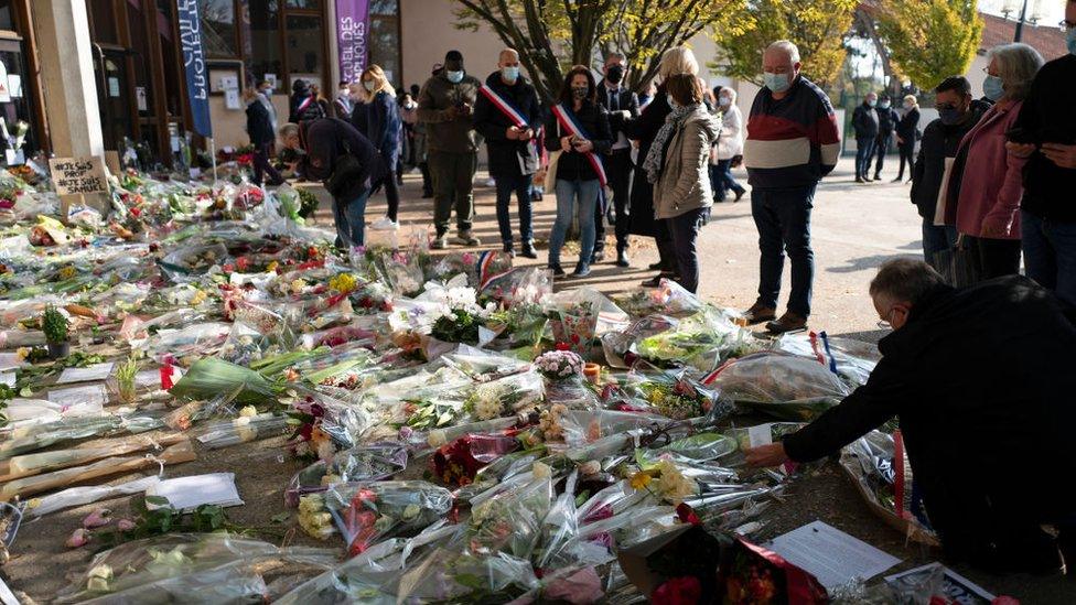 People have laid flowers in tribute to Samuel Paty outside the school where was murdered