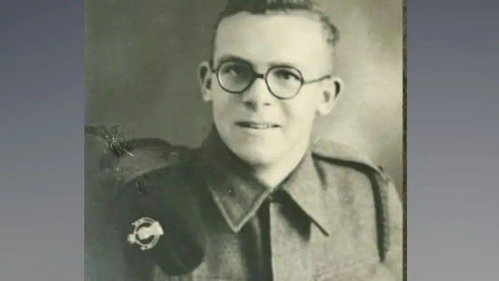 A black and white photo of Roy Hayward in military uniform wearing glasses and looking at the camera.