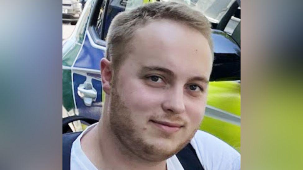 Ben Holden-Crowther in front of a police car