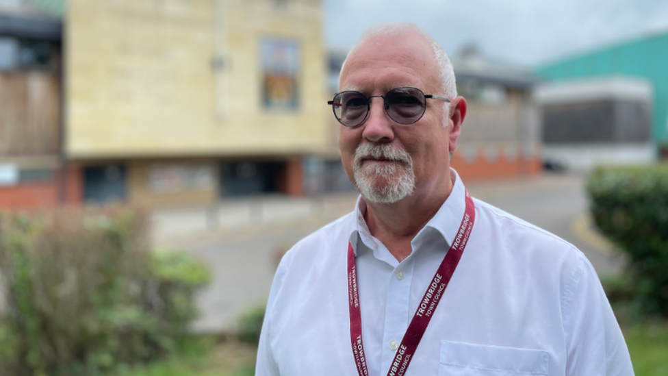 A man wearing a white shirt and red lanyard