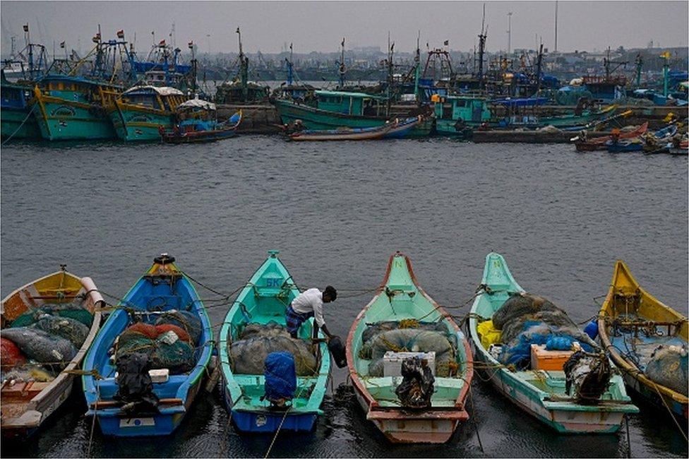 fisherman moors his boat amid high tide as dark clouds loom over the Kasimedu fishing harbor in Chennai on December 8, 2022, ahead of Cyclone Mandous forecasted landfall in north Tamil Nadu-south Andhra Pradesh coasts