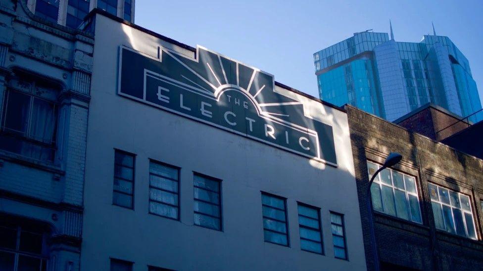 A white multi-storey building with a sign in Art Deco style that says "The Electric"