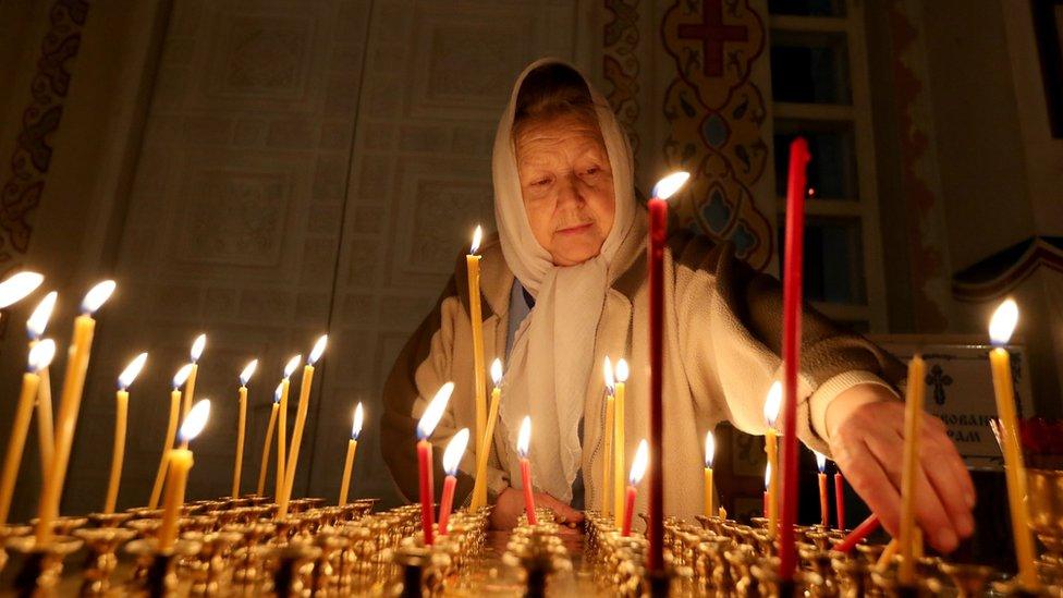 Woman lights candle at Christian Orthodox Church for Christmas