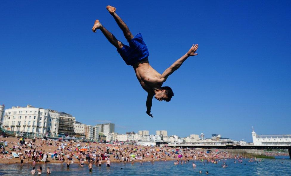 People jump into the sea from a groyne at Brighton beach in East Sussex