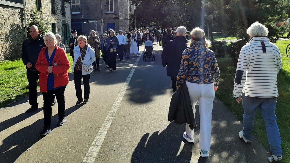 People join the back of the queue to pick up a wristband