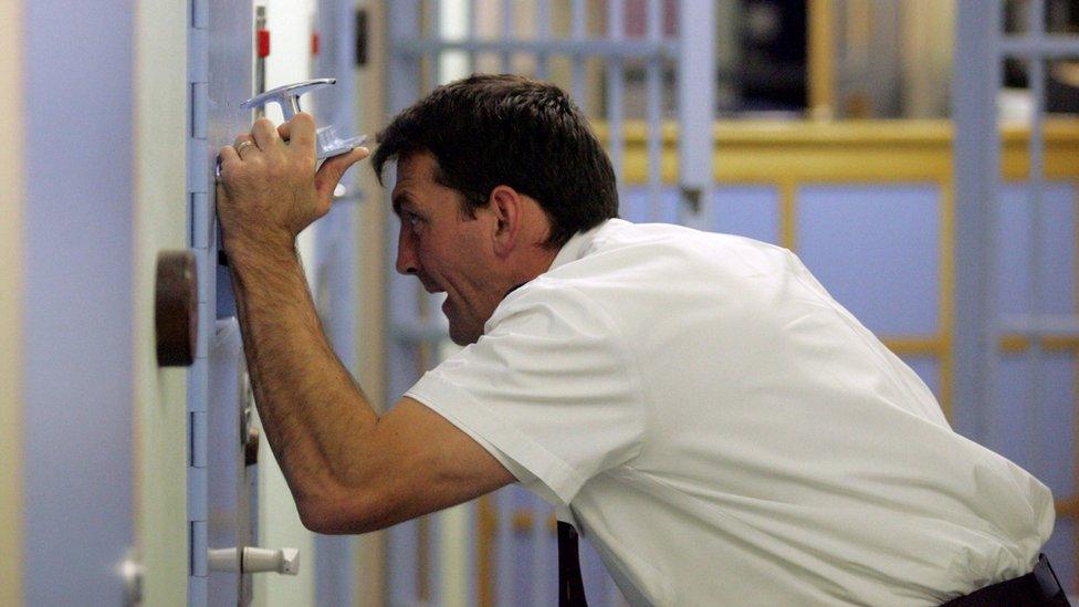 Police officer talks to detainee in a cell