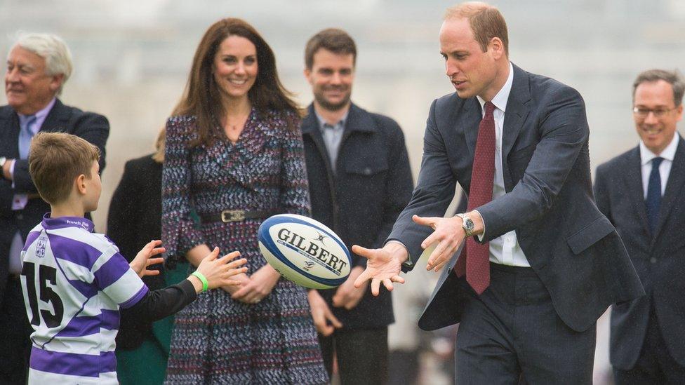 Prince William throws a rugby ball to a boy