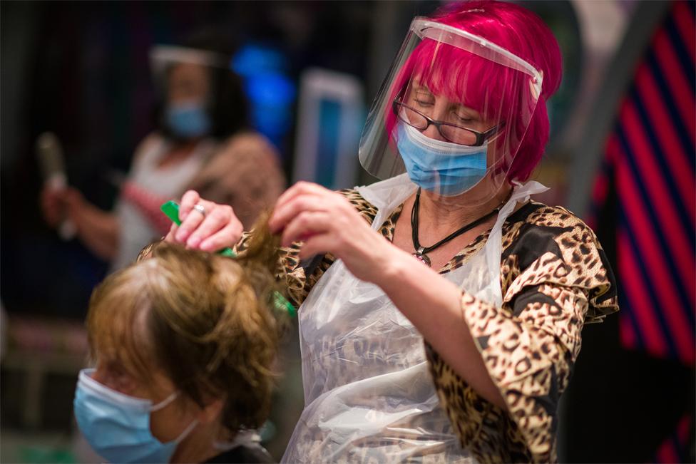 A hairdresser cuts a customer's hair