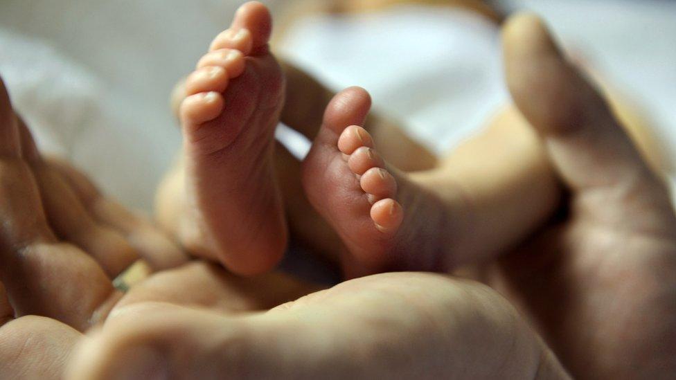 father holds baby's feet