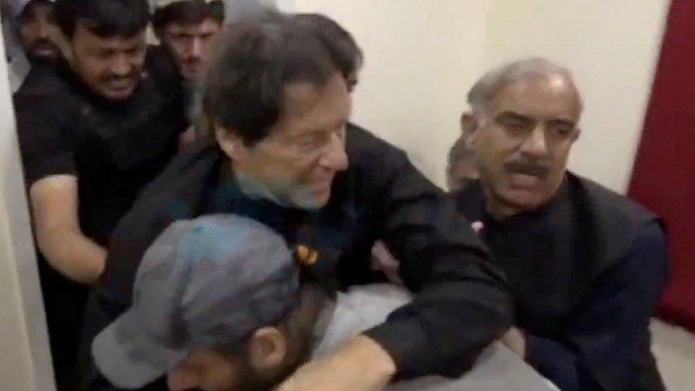 Former Pakistani Prime Minister Imran Khan is helped after he was shot in the shin in Wazirabad, Pakistan November 3, 2022 in this still image obtained from video.