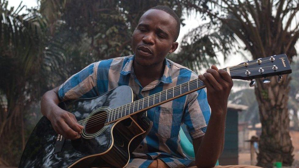 Emmanuel Ngallos sings one of his own compositions while sitting in the front yard of his family home in the Sango neighbourhood of Bangui.