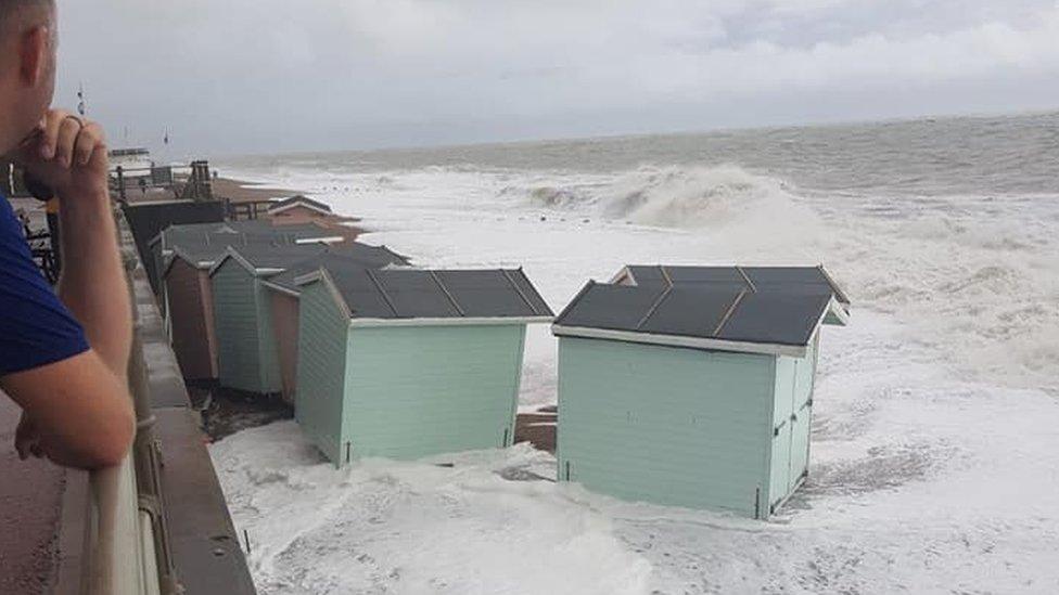 Beach huts lifted and washed down the beach by the waves