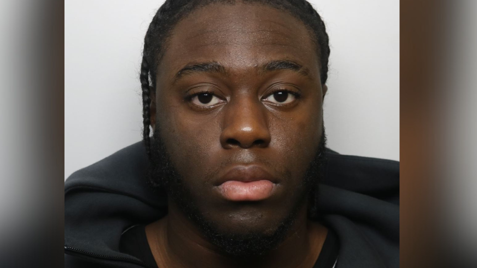 Paul looks blankly at the camera in his custody image. He has tightly braided hair and wears a black hoody. 