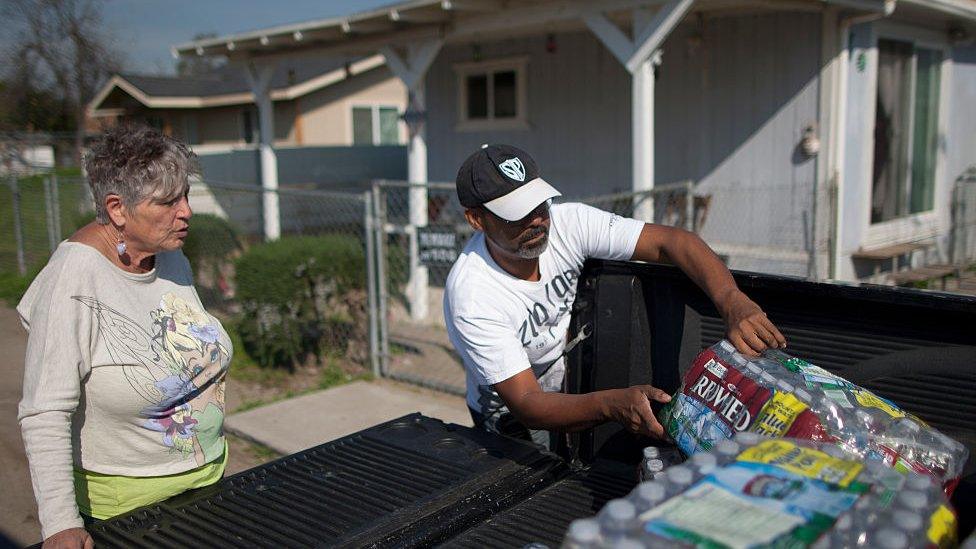 Rafael Surmay receives drinking water from Donna Johnson (L) who distributes drinking water to neighbors as water wells supplying hundreds of residents remain dry in the fourth year of worsening drought on February 11, 2015 in East Porterville, California.