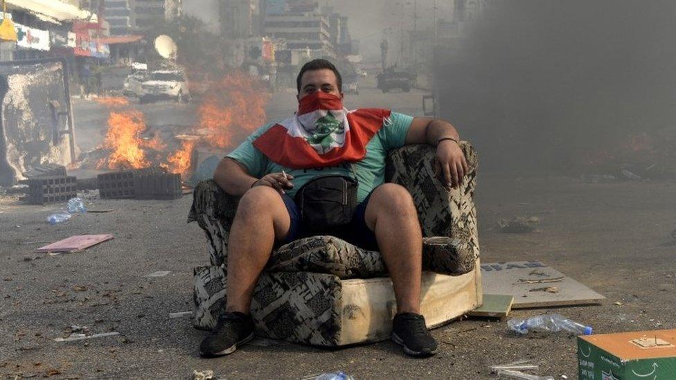 A man sits down in front of flames