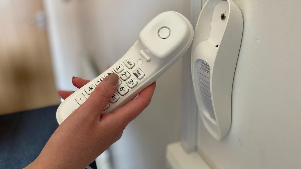 A hand holding the prison phone