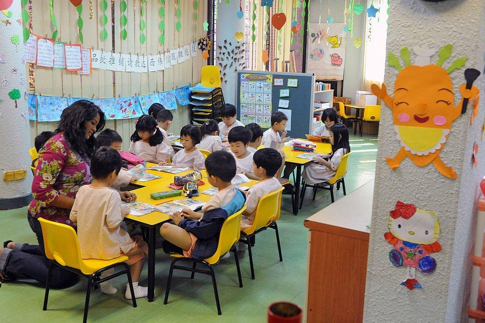 A teacher (L) guides children to read a story book during a lesson in Singapore on 25 May 2010.