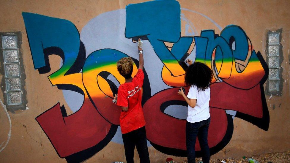 Sudanese revolutionaries paint murals along a wall in the Khartoum neighbourhood of Arkawit on 24 June 2020