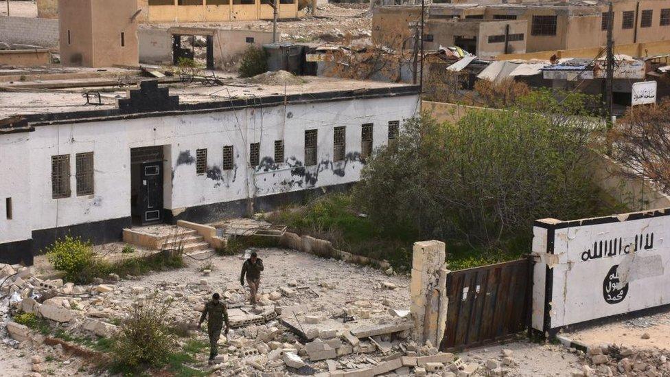 Syrian government forces walk among rubble on 30 March