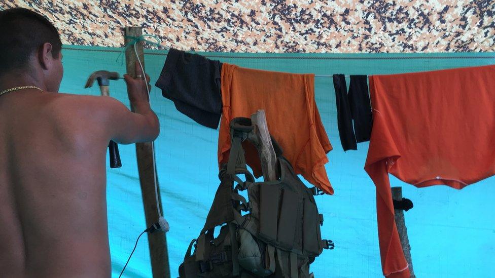 A Farc member puts a nail in a pole holding up a washing line in the Icononzo transition zone