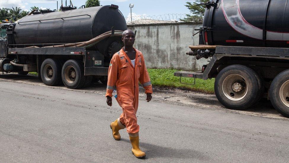 An employee walks past oil trucks at Port Harcourt in Nigeria.