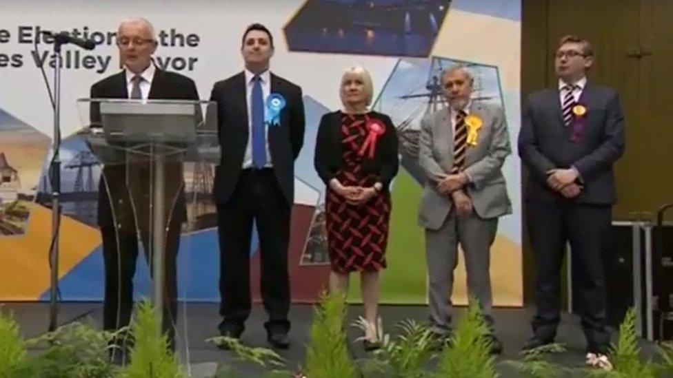 Candidates stand on a stage