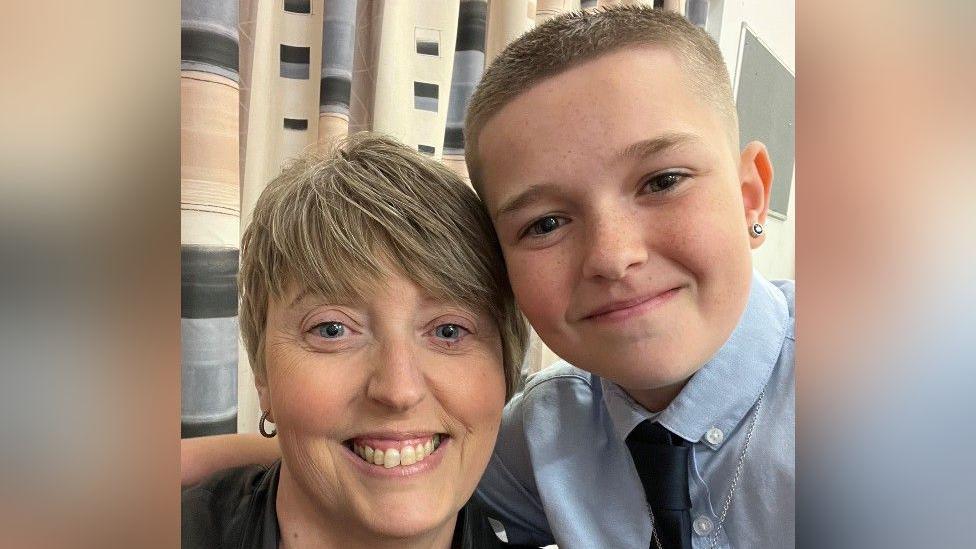 A selfie of Jodie and her son. Jodie has short blonde hair. Her son has his arm around her