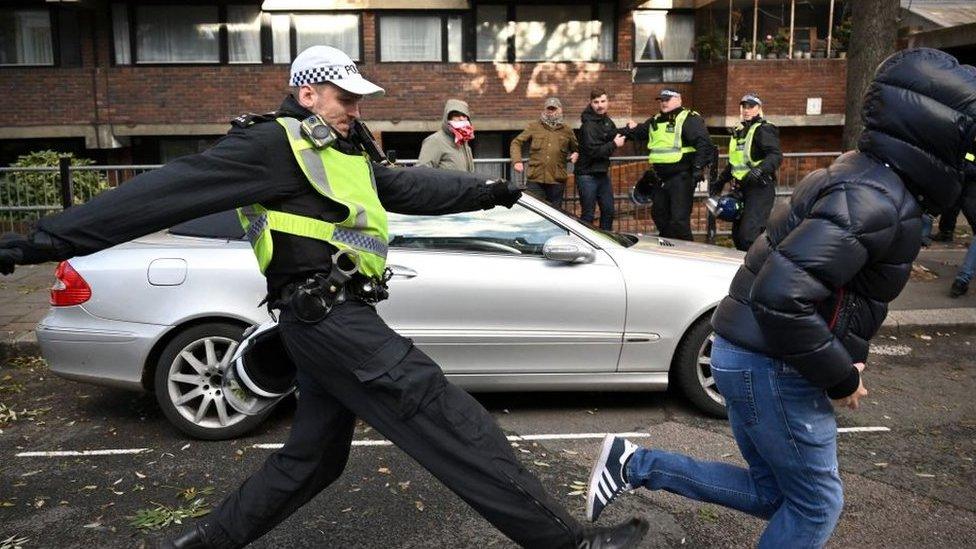 A police officer chases a man through streets close to the 'National March For Palestine' in central London on November 11, 2023, as counter-protest groups are monitored by police close to the route of the main march