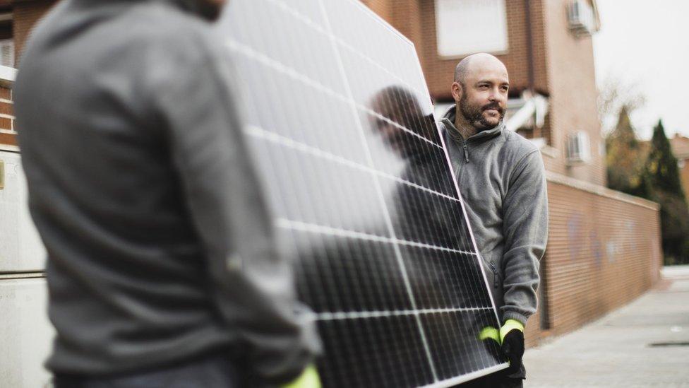 Workers moving a solar panel