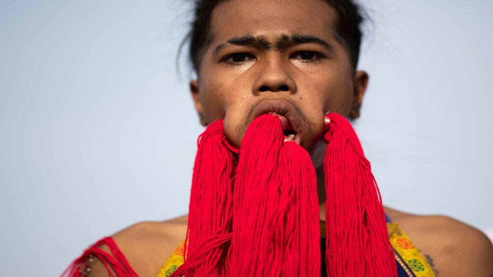 Performer with strings running across his pierced cheeks