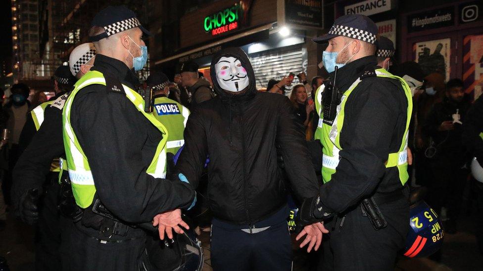 Police detain a protester during the Million Mask March anti-establishment protest at Trafalgar Square