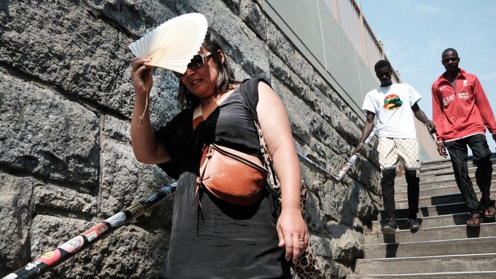 Woman uses fan to block out sun