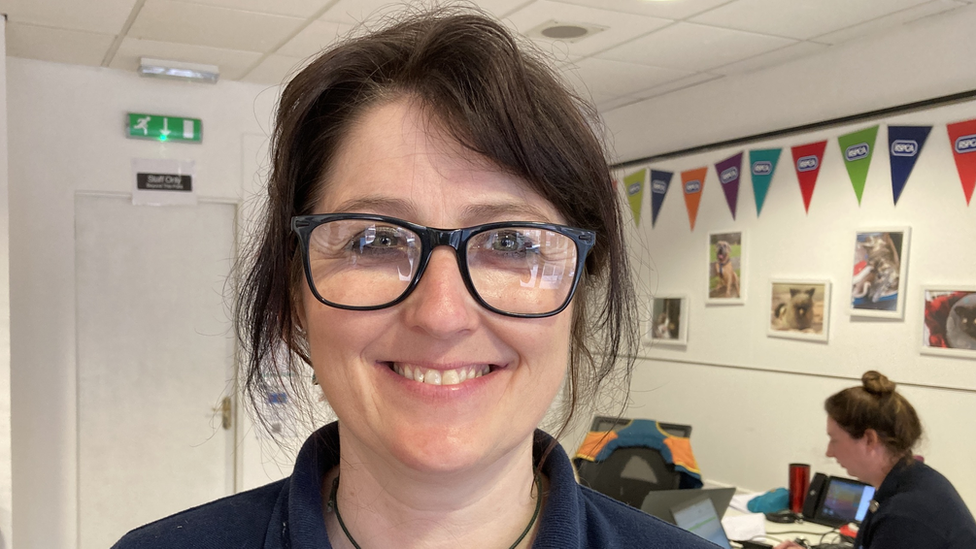 Woman with dark hair and spectacles stands at a clinic