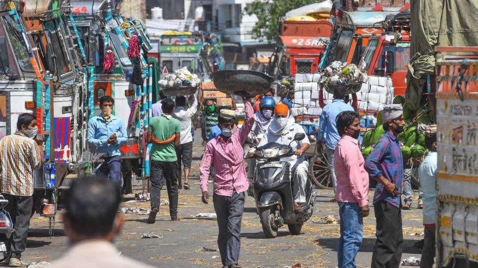 People carrying bundles of vegetables during lockdown, in Azadpur Mandi on May 7, 2020 in New Delhi, India