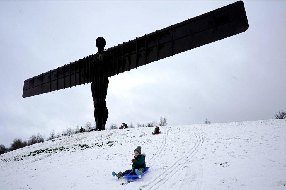 Boy sledging next to Angel of the North