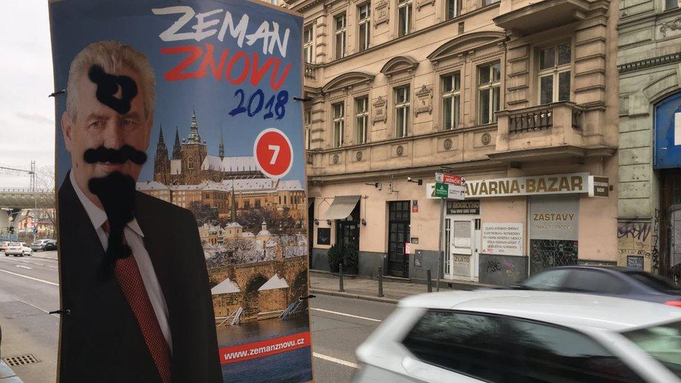 A defaced Zeman poster tied to a lamppost in Prague