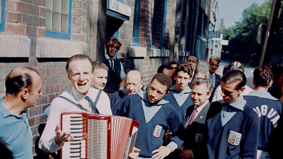 Uruguay's Julio Cortes (centre) and Luis Ramos (right) are intrigued by an accordion player