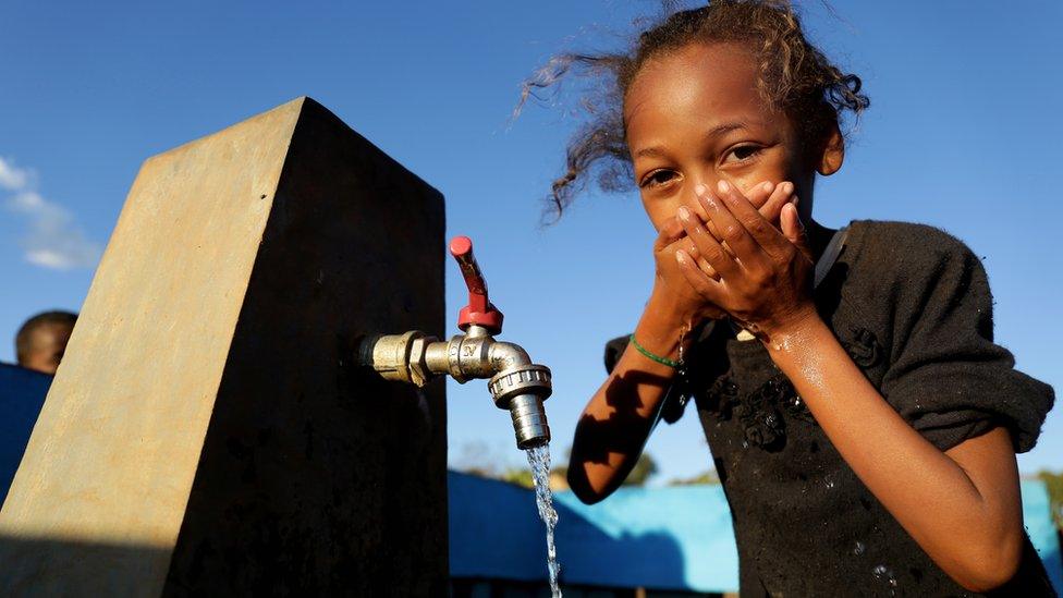 A child drinking water from a tap in a village in Madagascar