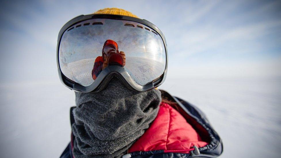 Person wearing a large pair of goggles - in icy Antarctic landscape... also a warm coat and scarf