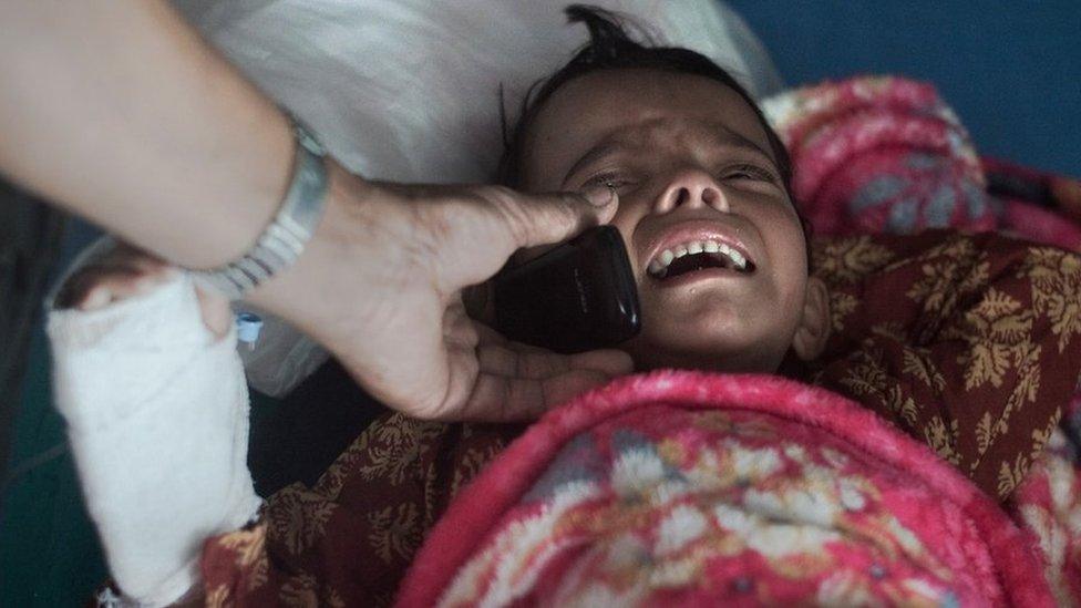 A young injured girl speaks to her mother via mobile after April's devastating earthquake in Nepal