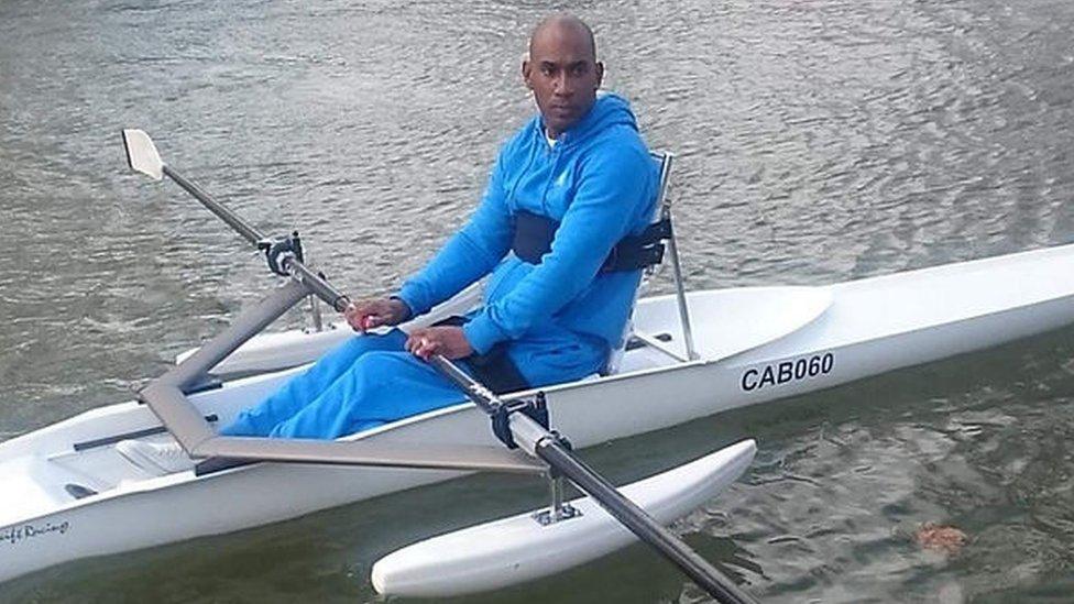 Ian Barrington in his rowing boat He is wearing a light blue tracksuit