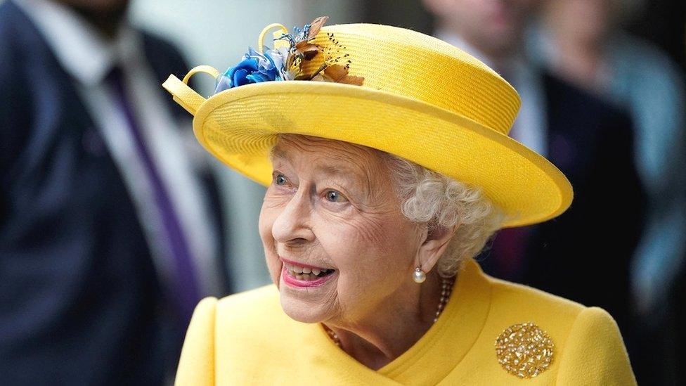 The Queen smiles in a yellow outfit during at Paddington station in central London