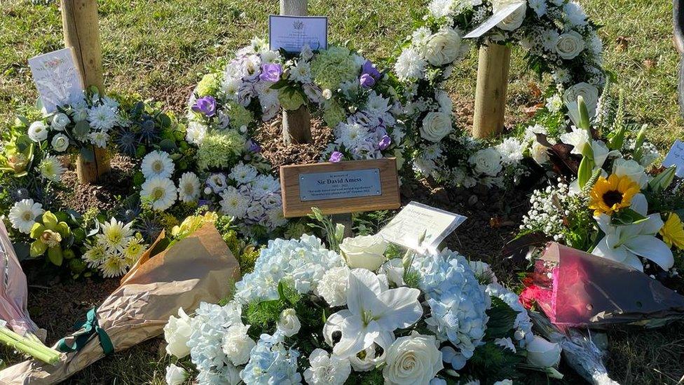 Floral tributes laid at the foot of a tree planted on the anniversary of Sir David Amess' murder