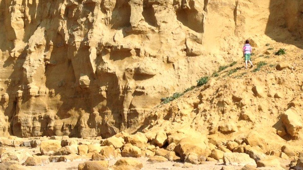 A child climbing on a collapsed section of cliff