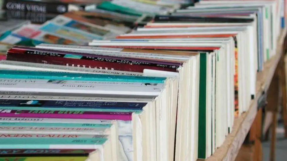 A generic photograph of books lined up in a row on a  table