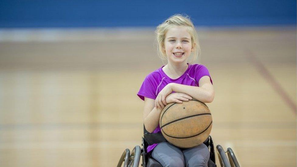 A young girl in a wheelchair playing basketball