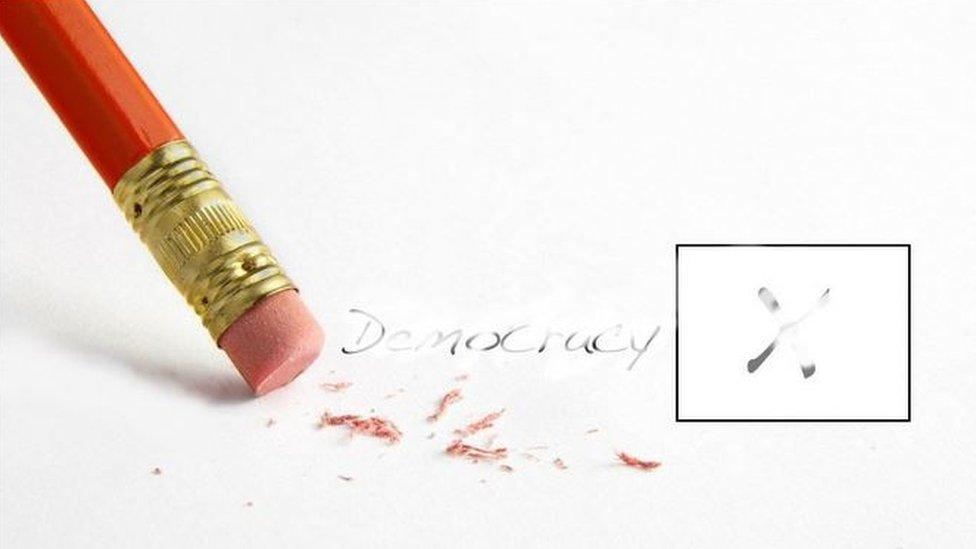 Picture of pencil written word "democracy" being erased