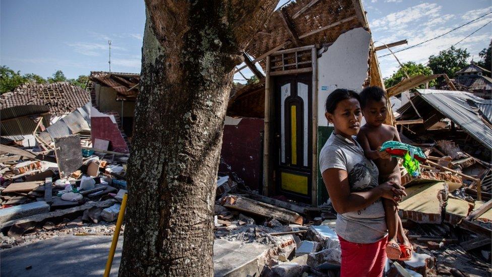 A woman with her son stands near the ruins of their home following an earthquake in Pemenang on 8 August 2018 in Lombok Island, Indonesia