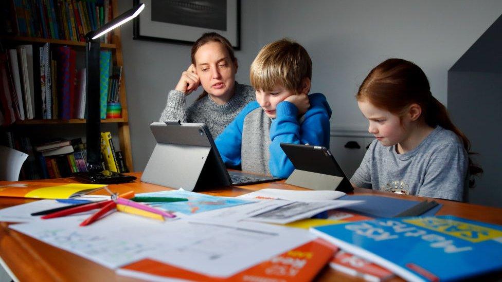 A young boy and girl learn with their mother.